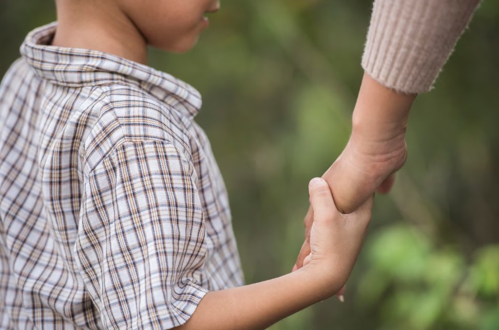 a young boy holding someone’s hand