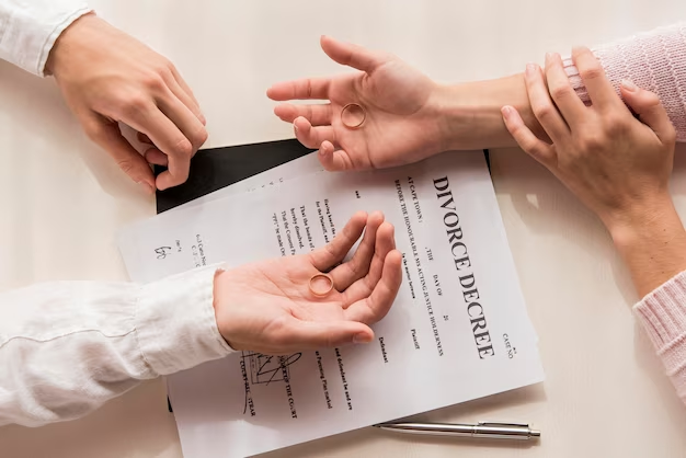 Two hands holding rings and divorce papers