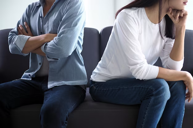 A man and a woman are sitting on the sofa on opposite sides