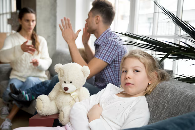 Upset girl against the background of her parents who are quarreling